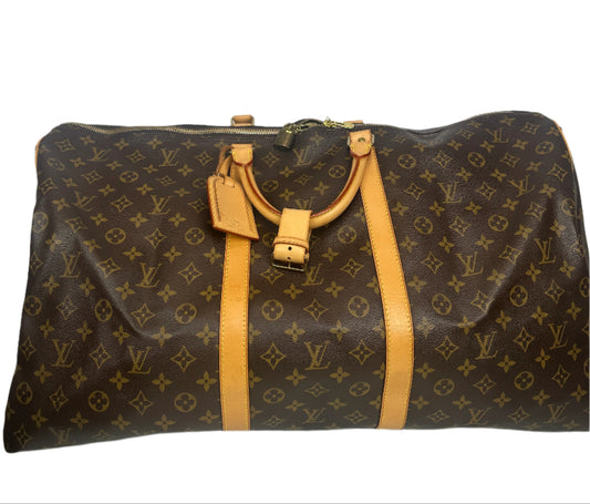 Louis Vuitton monogram bag with gold accents against a geometric-patterned wall.